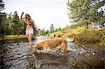 Young woman and dog paddling in river, Lake Tahoe, Nevada, USA