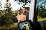 Rear view of romantic young couple kissing at riverside, Lake Tahoe, Nevada, USA