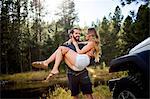 Romantic young man carrying girlfriend on riverside, Lake Tahoe, Nevada, USA