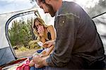 Young couple sitting in tent playing cards, Lake Tahoe, Nevada, USA