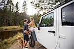 Romantic young couple next to jeep on riverside, Lake Tahoe, Nevada, USA