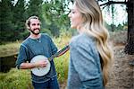 Young couple playing banjo at riverside, Lake Tahoe, Nevada, USA