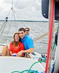 Couple relaxing on sailboat, looking at camera smiling