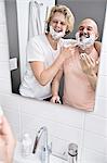 Bathroom mirror image of male couple having fun shaving