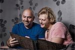 Male couple sitting up in bed looking at photo album