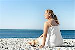 Smiling woman sitting on pebble beach