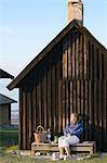 Woman resting near wooden house