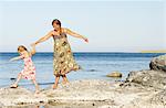 Mother with daughter walking on rocky coast