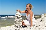 Woman on beach stacking stones