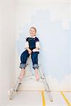 Girl with paint roller sitting on ladder