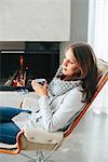 Woman drinking coffee in front of fireplace