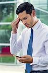 Businessman looking at cell phone with worried expression