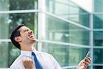 Businessman holding cell phone and celebrating good news