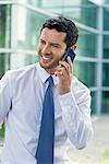 Businessman talking on cell phone and smiling outdoors