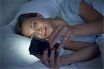 Woman in bed using smartphone