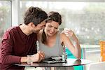 Couple in cafe watching video streaming on digital tablet