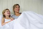 Mother and daughter watching tv together in bed
