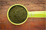 Nutrient-rich organic chlorella powder - measuring scoop against rustic wood