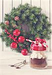 Hot chocolate mix with marshmallow in glass jar for christmas holiday drink and christmas wreath with decorations. Toned photo.
