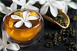 Cup of jasmine tea with bamboo scoop and blossom