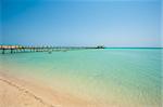 Long wooden jetty in the sea from a tropical island lagoon on beach