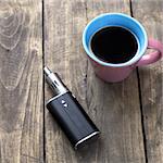 e-cigarette and cup of coffee on table, from above