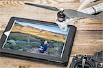 aerial photography concept - reviewing aerial picture of a drone operator on a digital tablet with a drone rotor and radio control transmitter