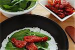 Casabe (bammy, beiju, bob, biju) - flatbread made from cassava (tapioca) with sun-dried tomatoes and  rucola (arugula) on pan. Selective focus