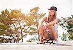 Young beautiful woman sitting on a skateboard outdoors