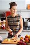 An elegant woman is standing in her kitchen, preparing apples to use to make applesauce and other fruit preserves. With a dash of cinnamon, the outcome will be delicious.