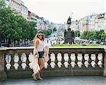 Happy trendy hippie woman tourist walking in the historical center of Prague. In the background Saint Wenceslas statue on Wenceslas Square in Prague. Tourism travel concept.