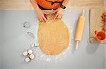 Closeup on housewife cutting out Halloween biscuits with pastry cutter. Traditional autumn holiday. Upper view