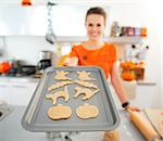 Closeup on woman holding tray of uncooked Halloween biscuits.  Halloween treats ready to go into oven. Traditional autumn holiday.