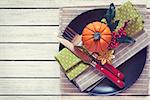 Festive autumn place settings with pumpkins and berries on white wooden table. Top view. Toned hpoto.