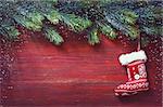 Old grunge red wooden board with Christmas border and knitted sock. Christmas card