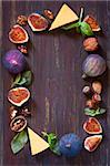Fruit cheese nuts frame on old wooden board with copy space for text.