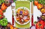 Tomato salad and fresh vegetables and herbs for cooking.