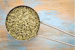 sea lettuce flakes in a metal measuring scoop  against grunge wood