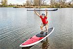 senior male paddler stretching and warming up on a paddleboard before paddling workout on a lake in Colorado