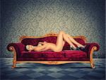 Naked woman with heels lying on sofa