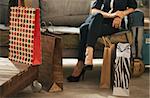 Close up on colourful shopping bags and elegant woman sitting on couch in modern loft apartment in background. Luxurious life concept