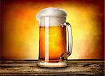 Beer in mug on wooden table and yellow background