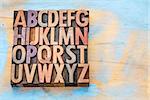alphabet abstract in vintage letterpress printing blocks stained by color inks against painted wood with a copy space