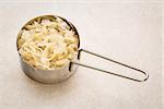 metal measuring scoop of sauerkraut against ceramic tile - healthy eating concept (probiotic food)