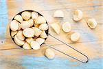 macadamia nuts in a metal measuring scoop (1/2 cup) against rustic barn wood