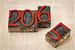 new year 2016 replacing the old year 2015 - letterpress wood type stained by red ink on a burlap canvas