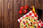 Italian pizza with cheese, tomatoes, olives and basil on wooden table. Top view with copy space