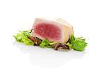 Delicious tuna steak on green salad isolated on white background. Culinary seafood eating.