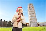 Young, itching from energy and searching for excitement. I'm going to Christmas trip to Italy. It is a no-brainer. Portrait of smiling woman in Santa hat in front of Leaning Tour of Pisa.