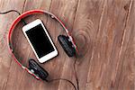 Headphones and smartphone on wooden desk table. Top view with copy space